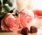 Два розовых роз с двумя конфет в форме сердца
